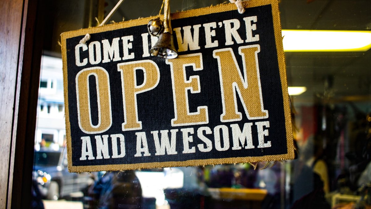 A restaurant door with an open sign and people inside